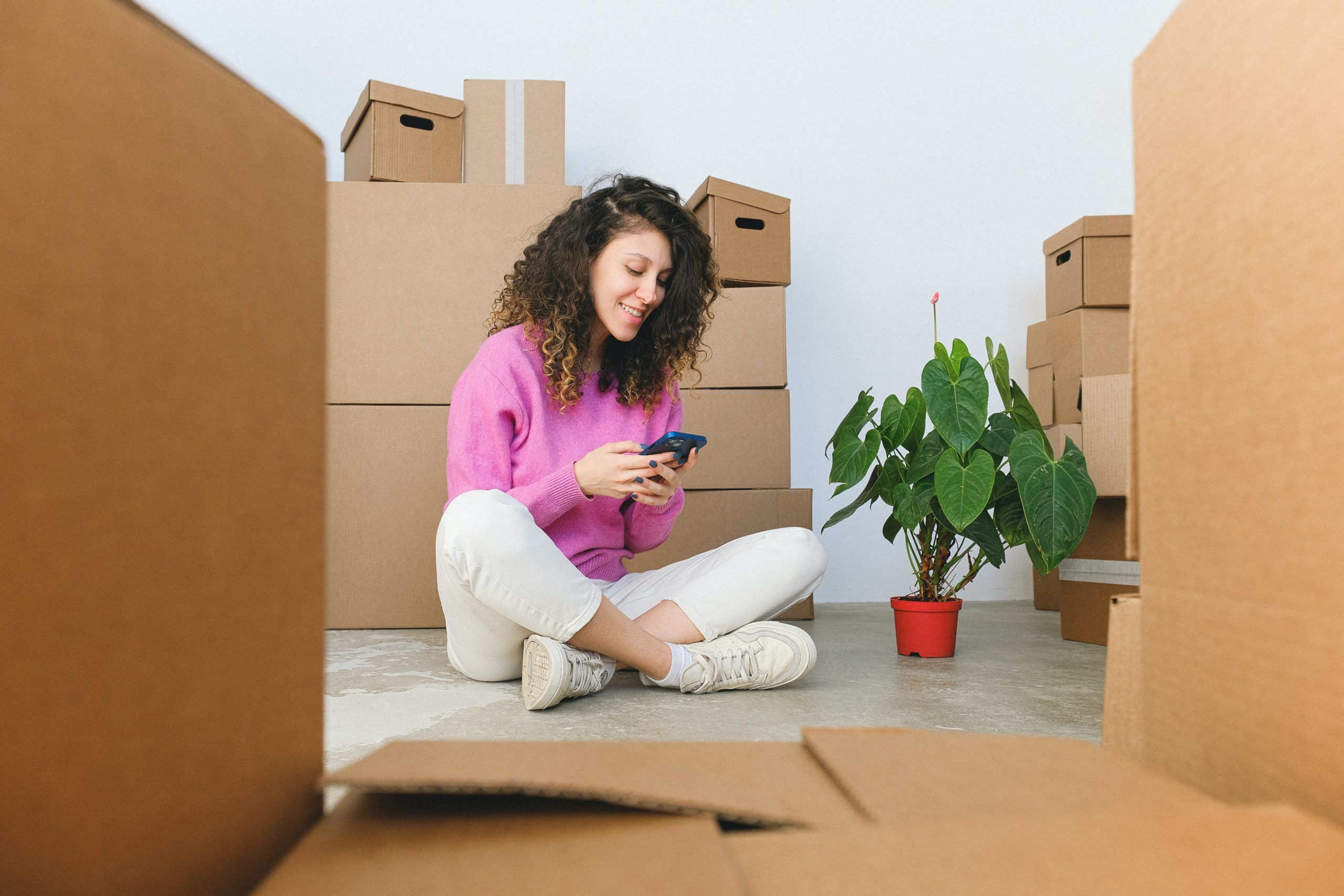 woman looking at her mobile in a place full of boxes