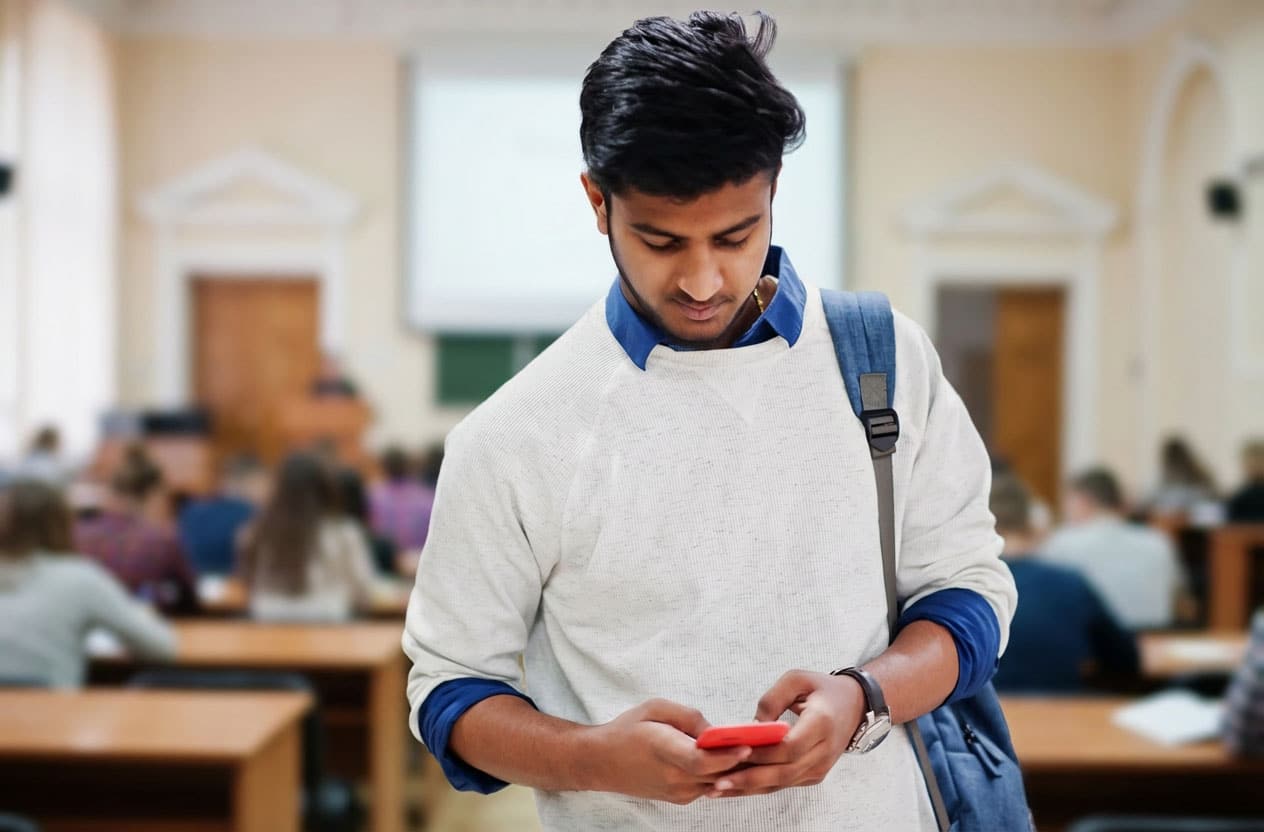 Student receiving sms message from university in classroom